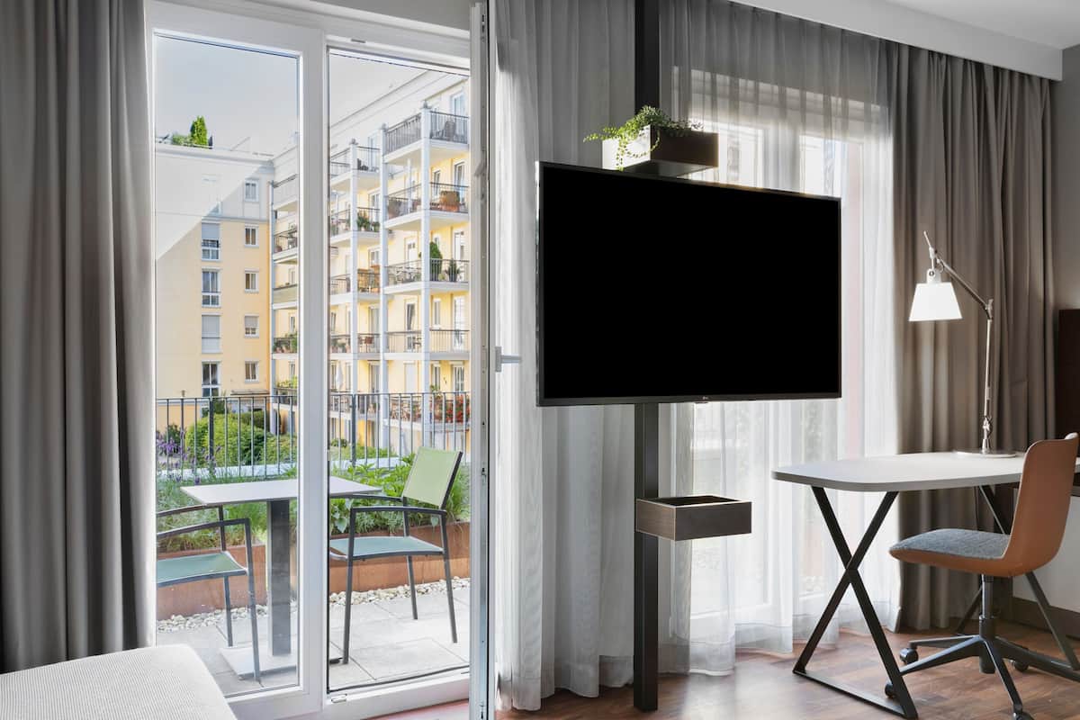 A modern hotel room with a large TV, a desk, and a chair.