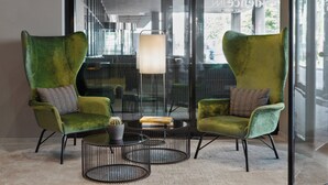 A modern lounge area with two green armchairs, a round coffee table, and a hanging light fixture. - Residence Inn by Marriott Munich City East (Munich)