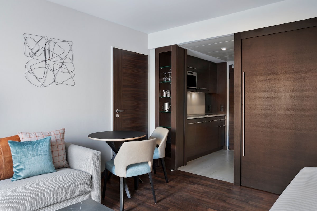 A modern room with a dining area, a kitchen, and a wardrobe.