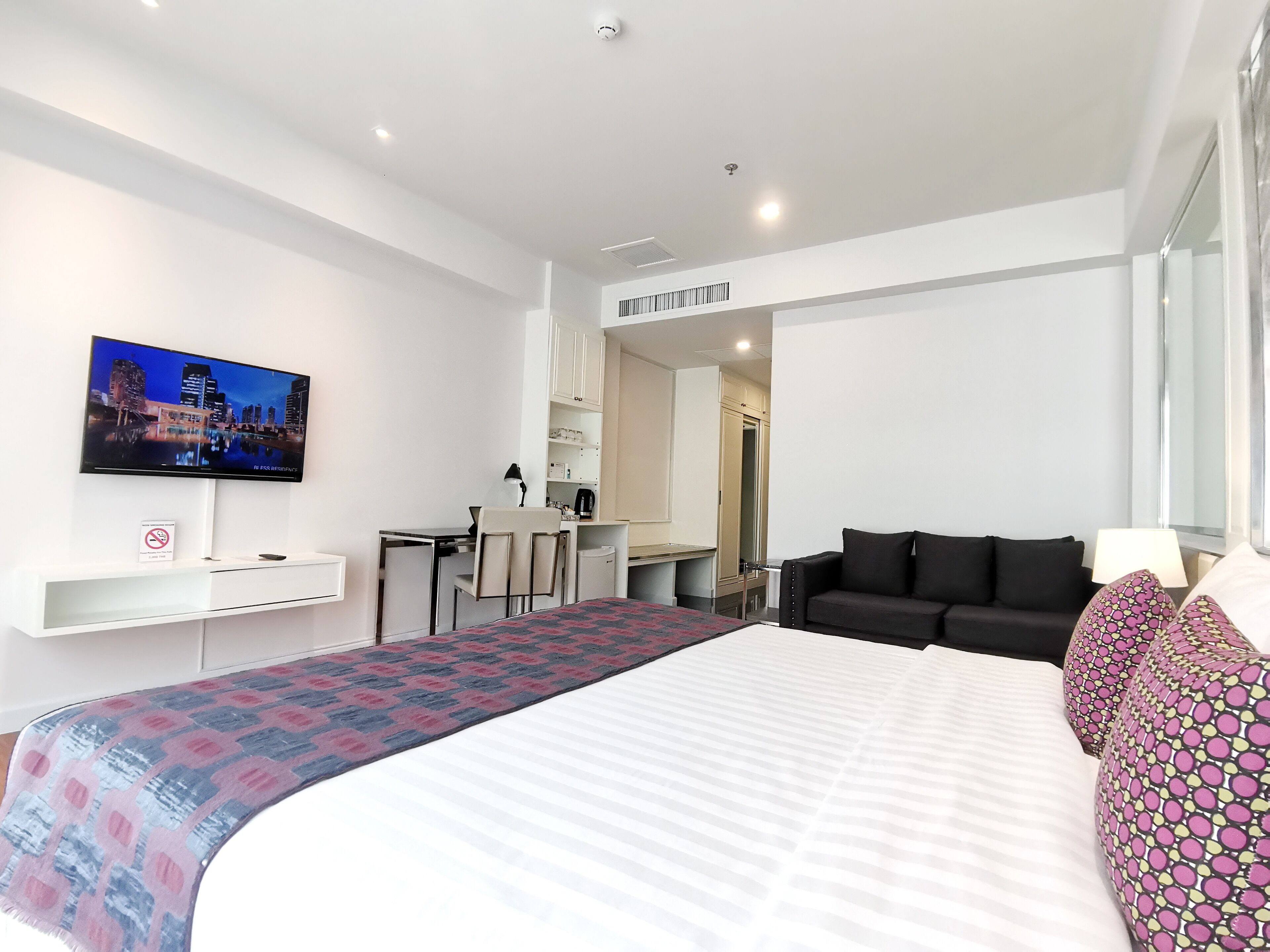 Ein modernes Hotelzimmer mit einem großen Bett, einem Schreibtisch mit Stuhl, einem Fernseher und einem Sofa.