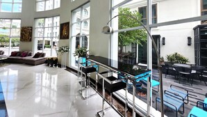A spacious room with large windows, a sofa, a coffee table, and a balcony with outdoor seating. - The Bless Hotel and Residence (Bangkok)