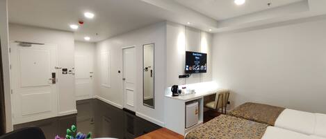 Ein Hotelzimmer mit Bett, Schreibtisch, Fernseher und Spiegel.