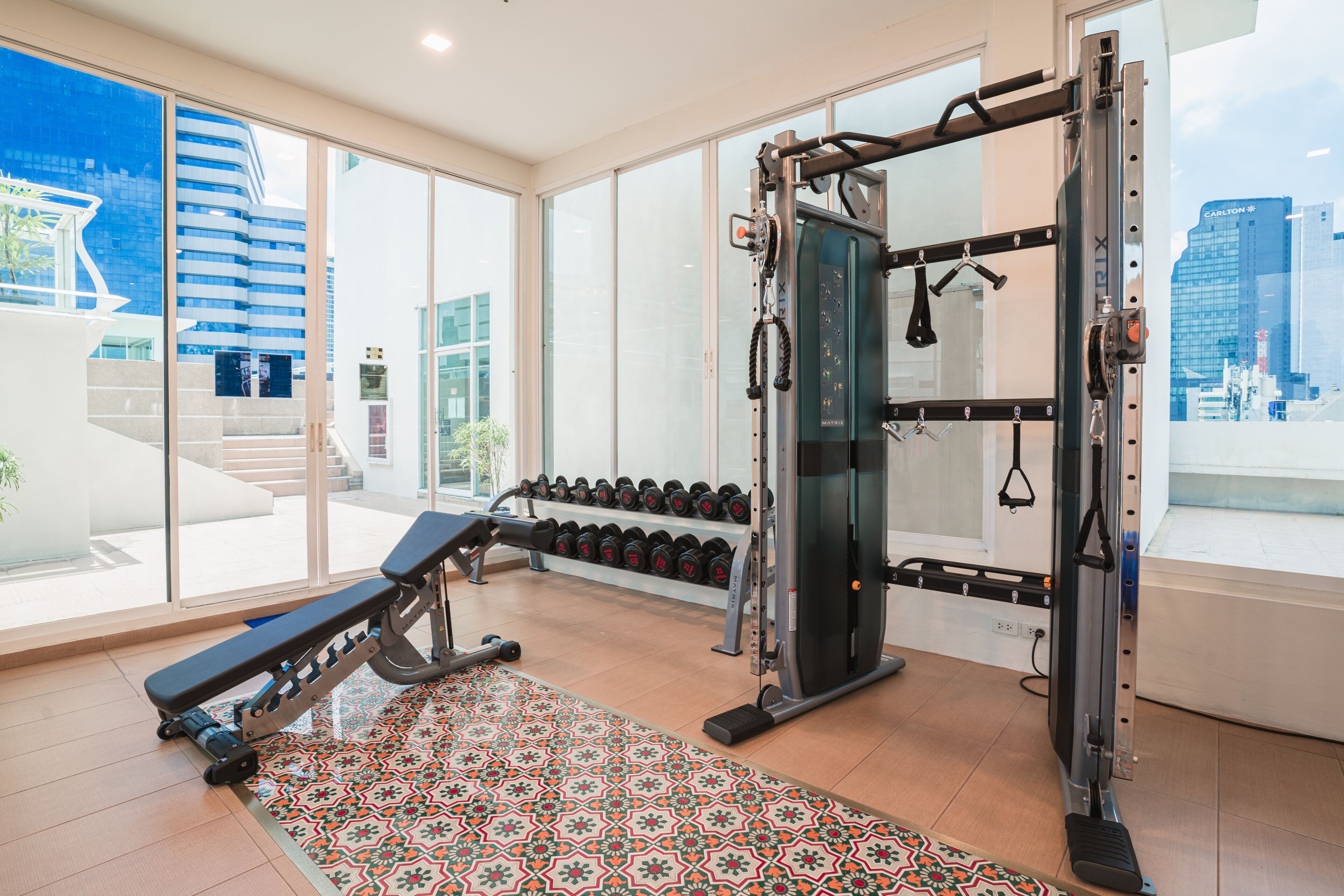 A gym with weightlifting equipment, dumbbells, and a bench.