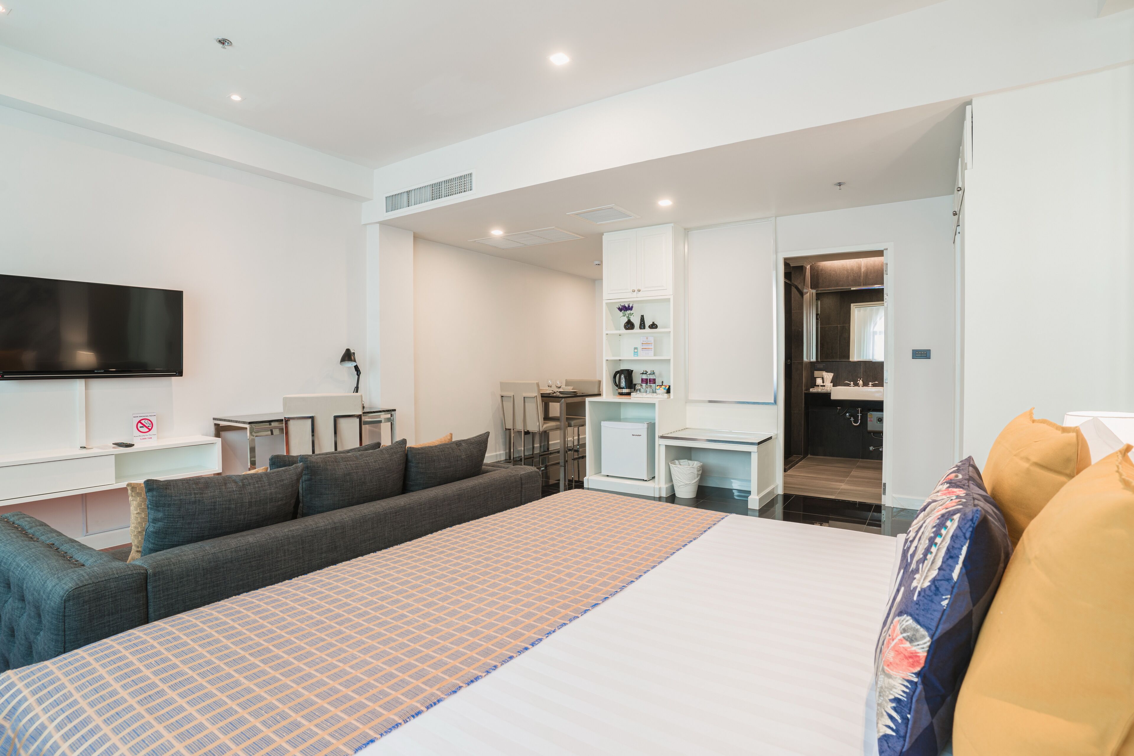Une chambre d’hôtel moderne dotée d’un grand lit, d’une télévision à écran plat, d’un bureau et d’un coin salon.