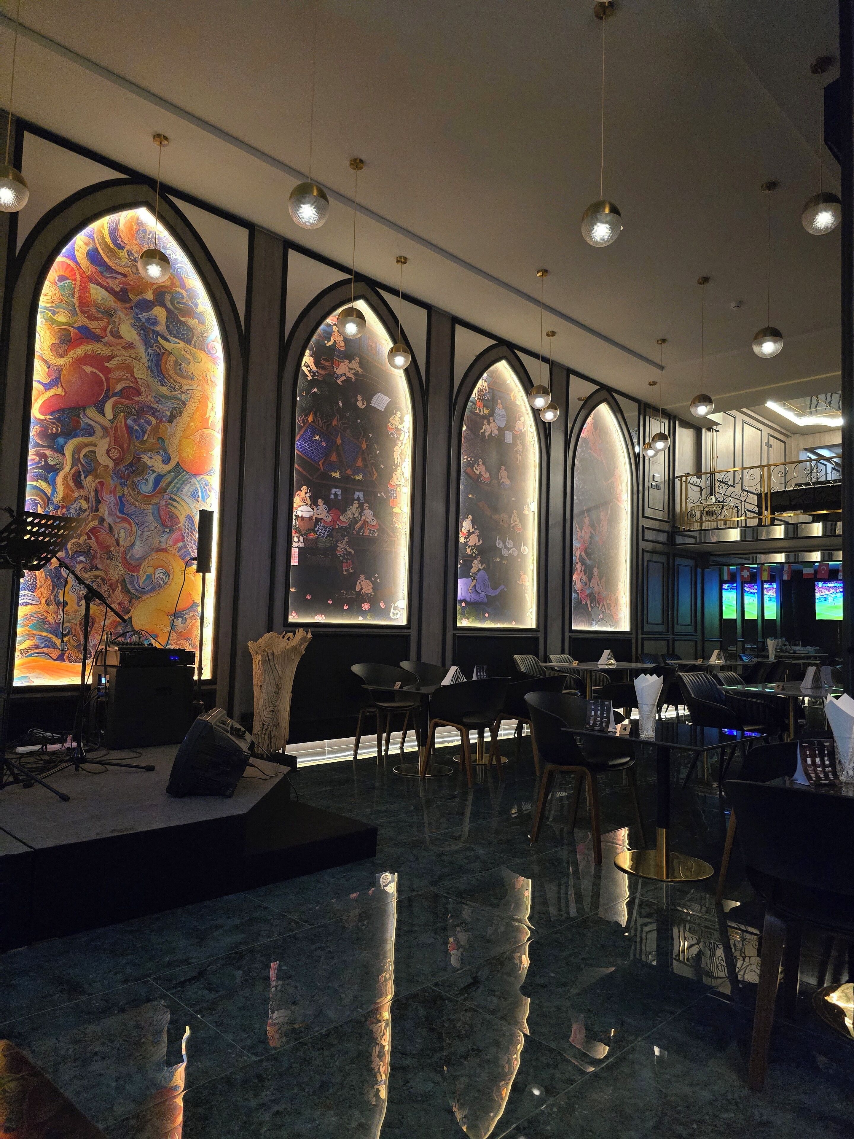 Un interior moderno con ventanas arqueadas, un escenario con equipo musical y una zona de bar.