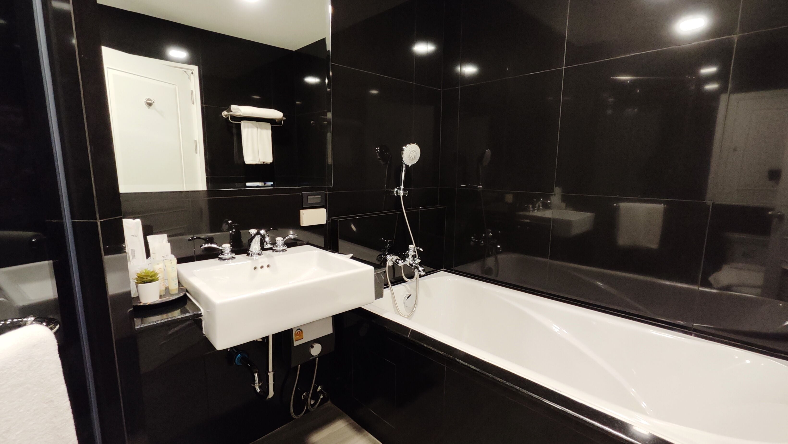 A modern bathroom with a white sink, a bathtub, and a mirror.