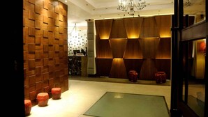 A lobby with a wooden wall, a glass floor-to-ceiling panel, and a chandelier. - The Blowfish Hotel (Lagos)