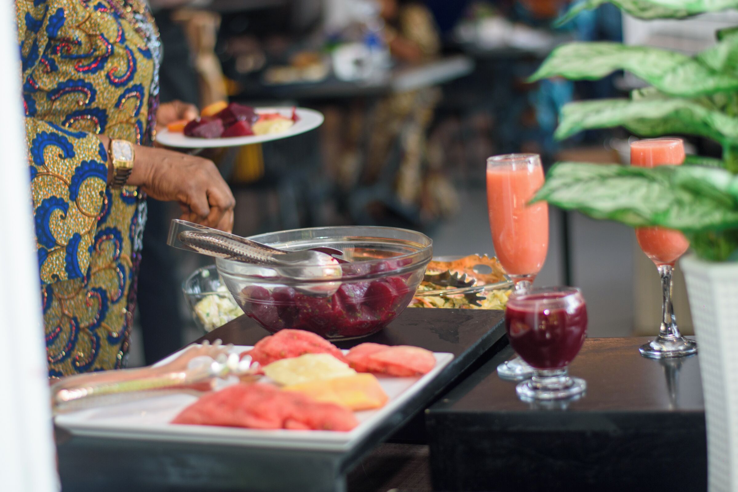 A buffet setup with various fruits and a drink station.