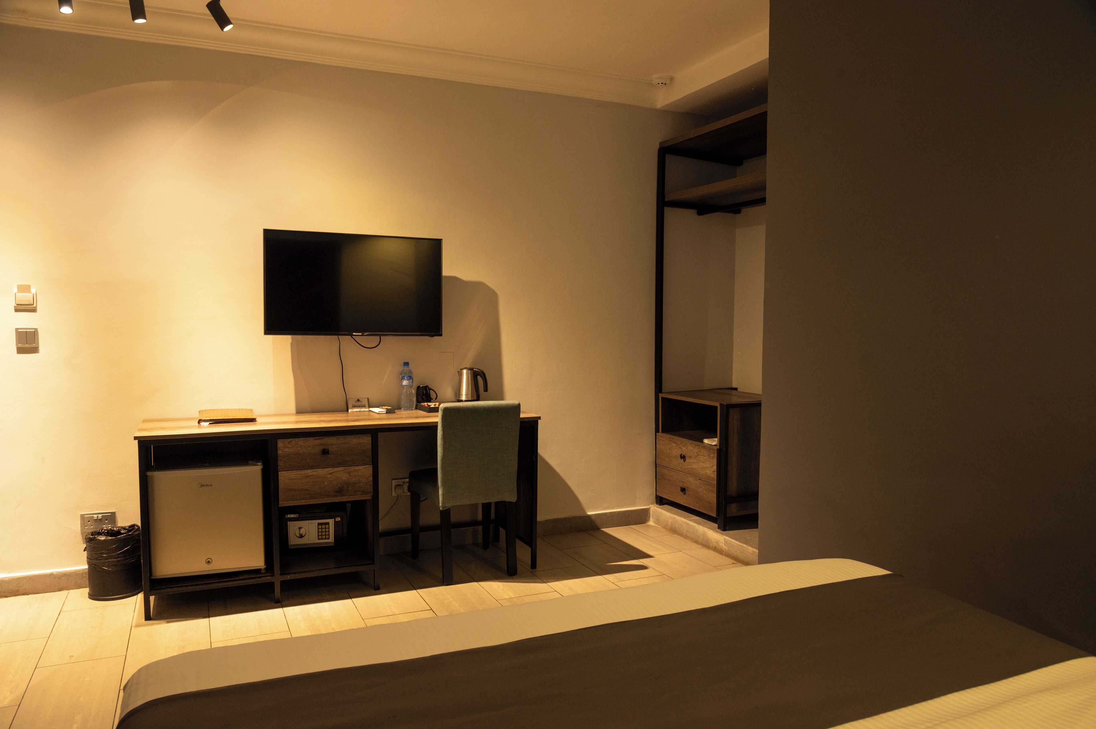 A hotel room with a desk, chair, television, and a wardrobe.