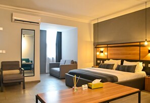 Relax in a spacious room with a large bed, comfortable armchair, and modern amenities.