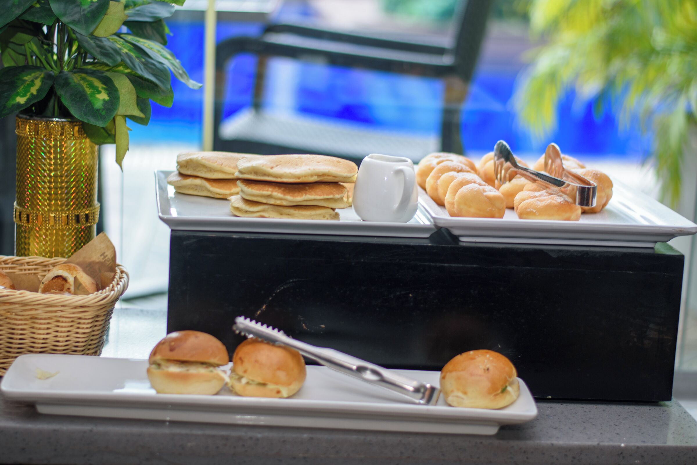 A buffet table with various food items including bread rolls, pastries, and sandwiches.