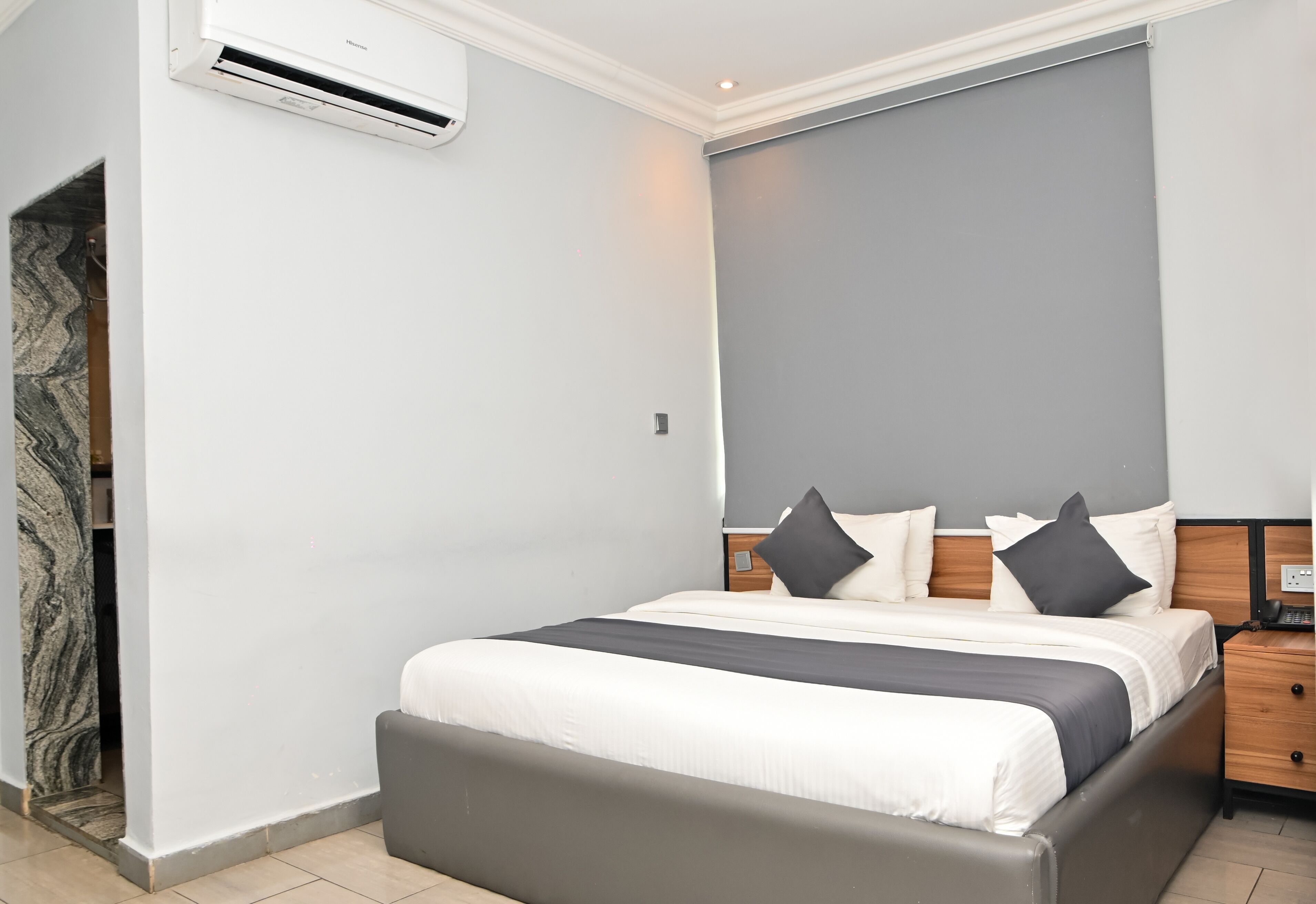 Quarto moderno com uma cama grande, uma mesa de cabeceira e parede com padrão marmorizado.