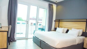 A hotel room with a large bed, a desk, and a view through a sliding glass door. - The Blowfish Hotel (Lagos)