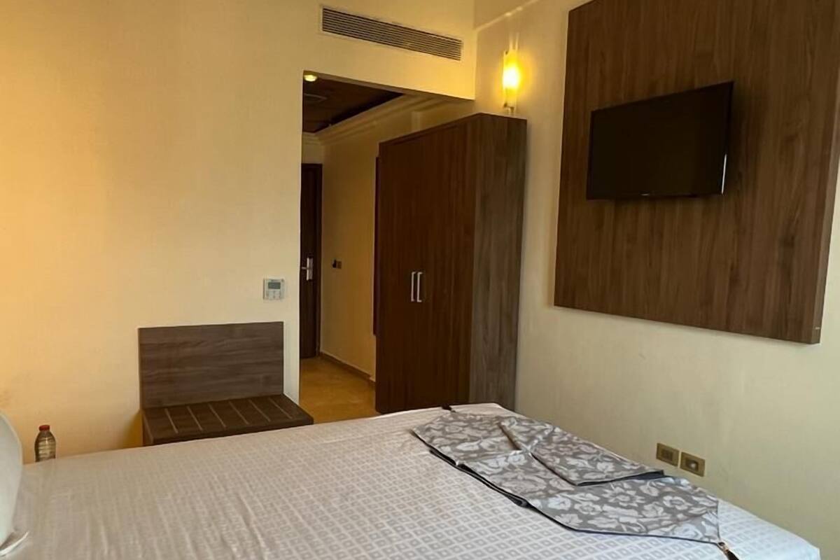 A bedroom with a bed, a TV mounted on the wall, and a wardrobe.
