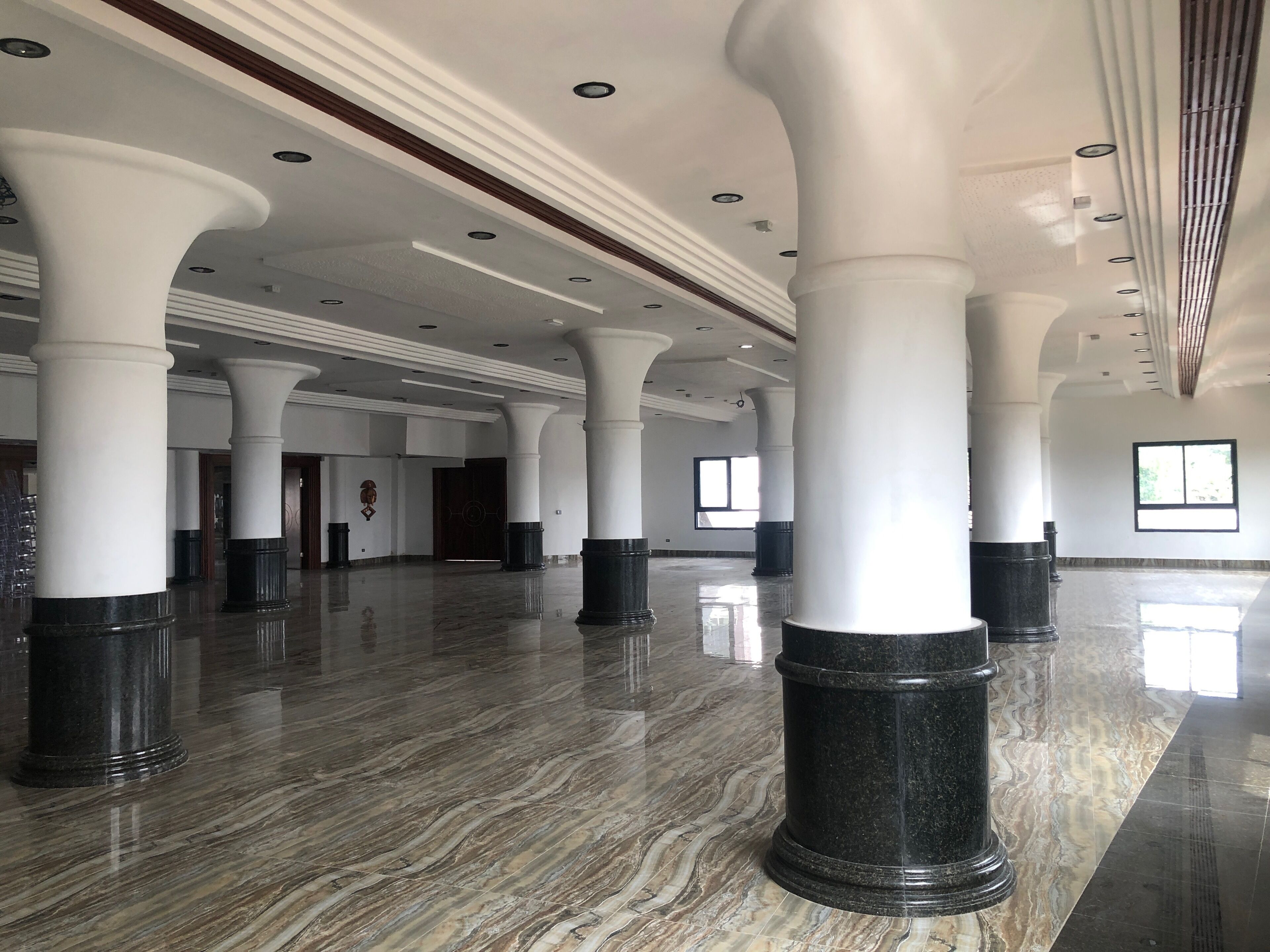 Un hall d’entrée spacieux avec de hauts plafonds, un sol en marbre et de grandes colonnes blanches.