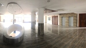 Un hall d’entrée spacieux, doté d’un sol en marbre, de grandes colonnes et d’une œuvre sculpturale centrale.