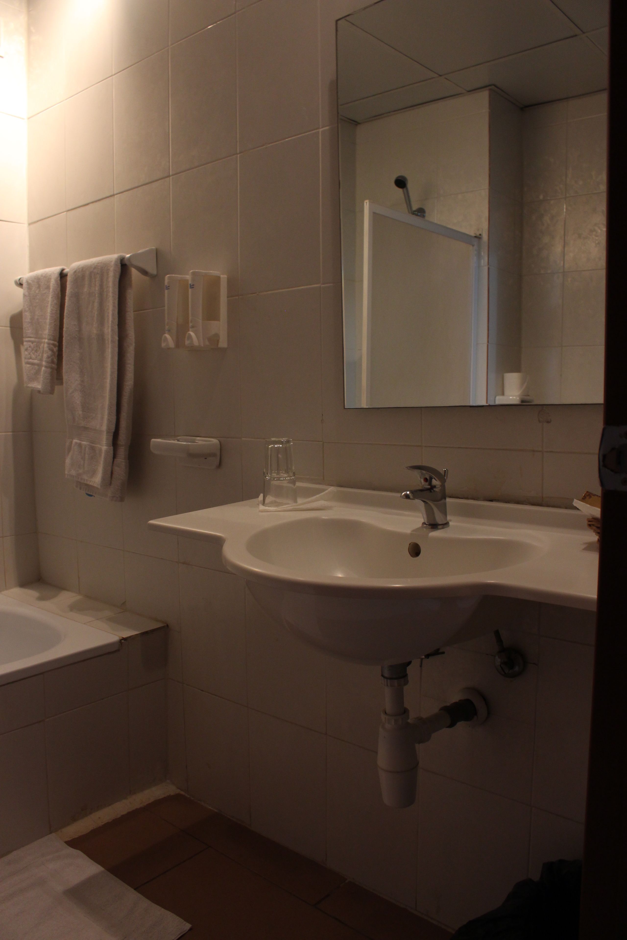 Une salle de bain avec un lavabo, un miroir et un porte-serviettes.