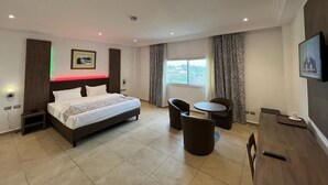 Une chambre d’hôtel avec un lit, un bureau, une chaise et un téléviseur.