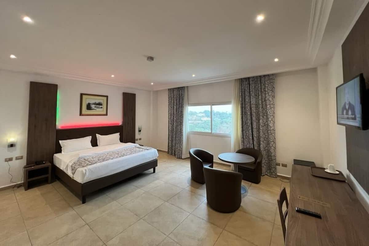 A hotel room with a bed, a desk, a chair, and a TV.