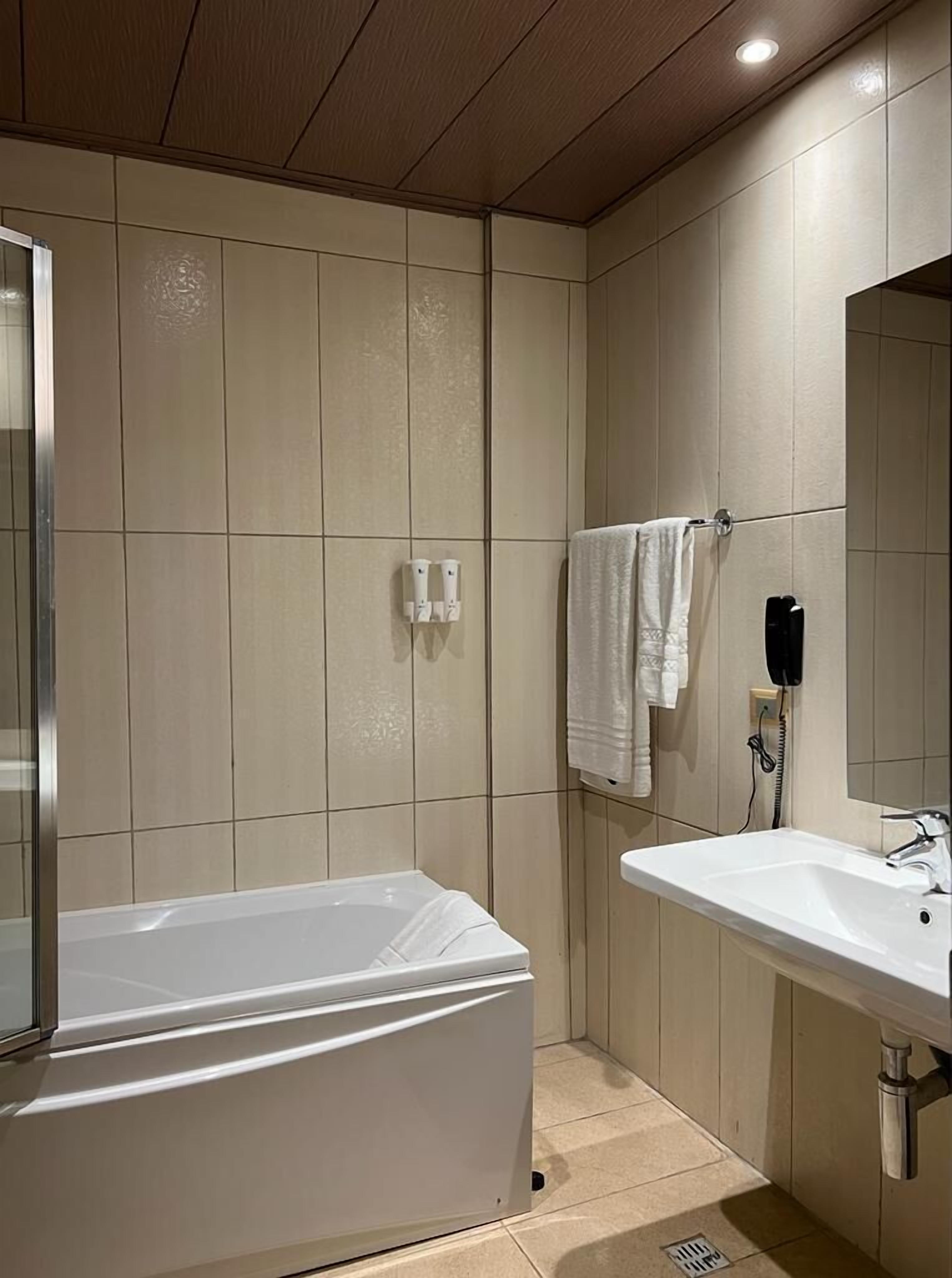 Un baño moderno con bañera, lavamanos y espejo.
