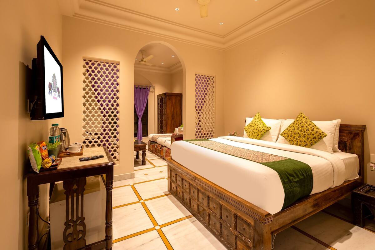 A hotel room with a large bed, a desk, a television, and a decorative wall.