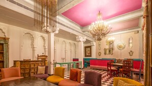 A spacious lobby with a checkered floor, a central seating area with colorful cushioned chairs, and ornate chandeliers. - Jyoti Mahal A Royal Heritage Hotel - 5 Mins from New Delhi Railway station & 2Mins From Metro (New Delhi)