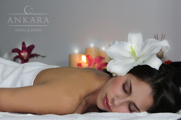Mulher deitada sobre uma toalha branca, com uma flor branca na cabeça e velas ao fundo.