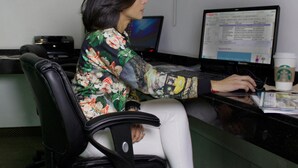 A person seated at a desk with two monitors, a laptop, and a coffee cup. - Hotel Ankara Las Lomas (San Luis Potosi)