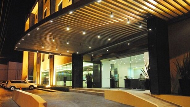 A modern hotel entrance with a covered outdoor area, a reception desk, and a car parked outside. - Hotel Ankara Las Lomas (San Luis Potosi)