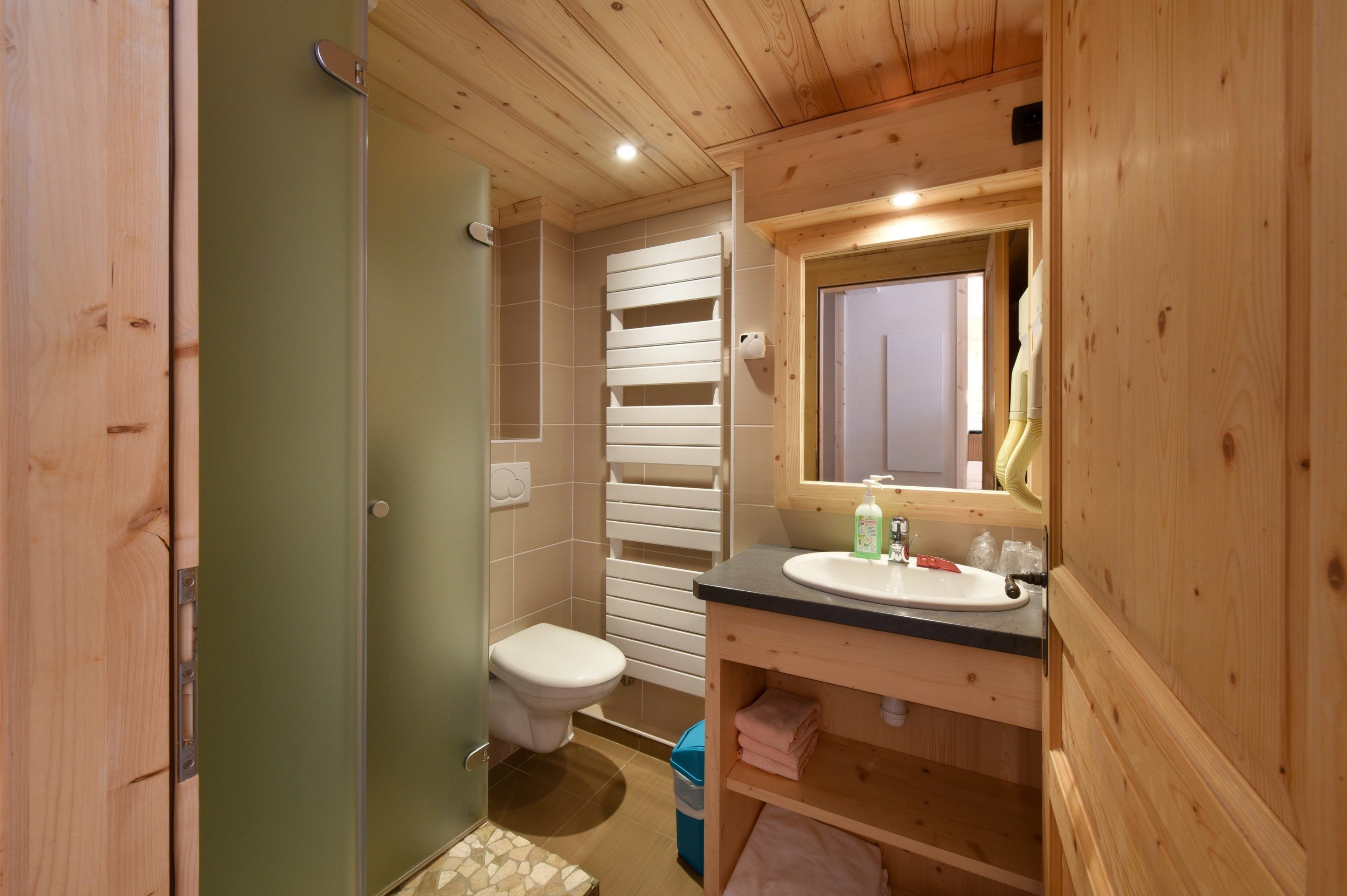 Un baño pequeño y funcional con tocador de madera, inodoro y zona de ducha.