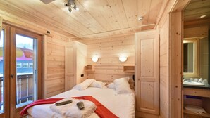 A wooden cabin bedroom with a bed, a red blanket, and a mirror above the bed. - Loc Hotel Alpen Sports (Les Gets)