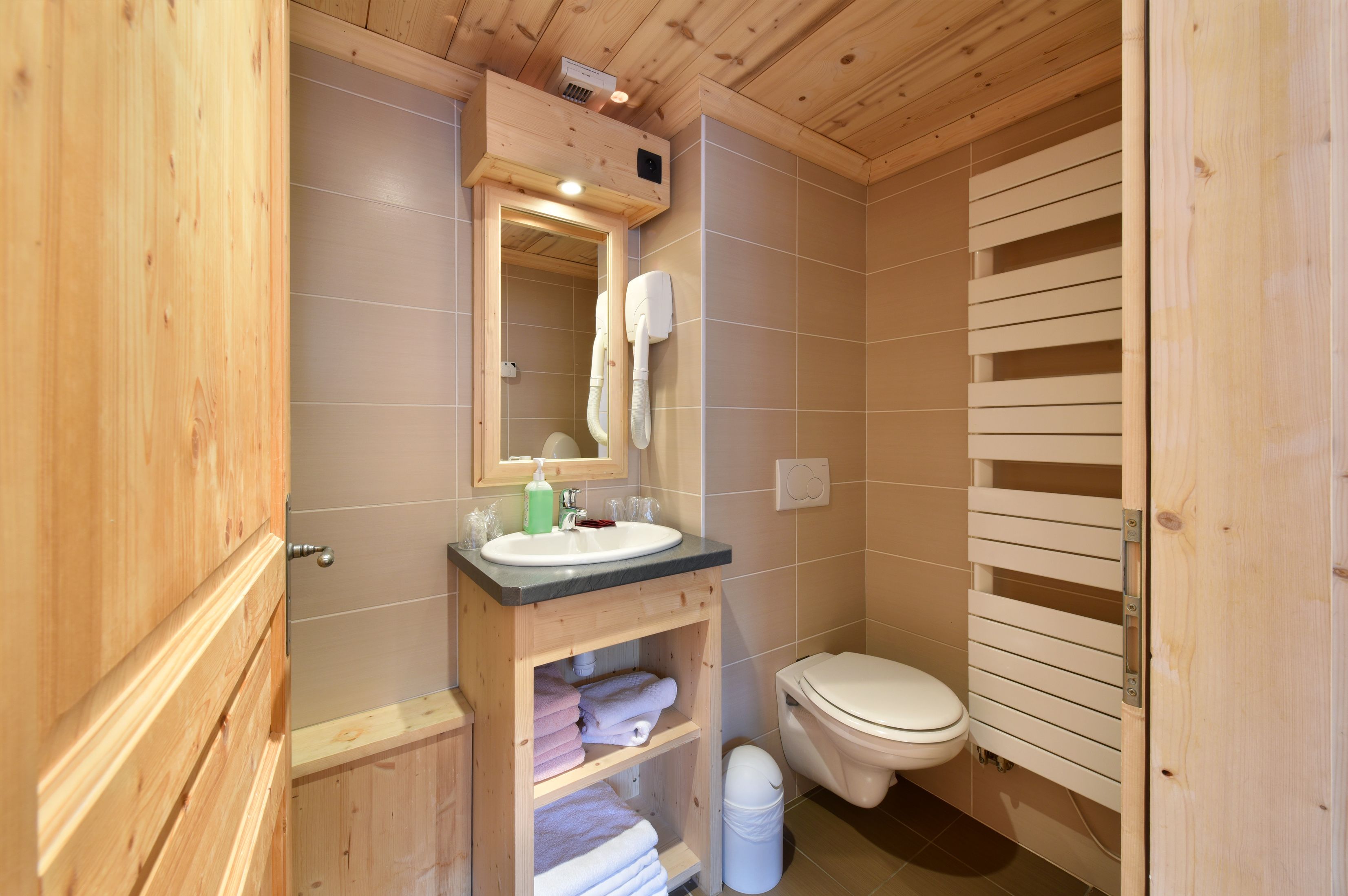 A wooden bathroom with a sink, mirror, and toilet.