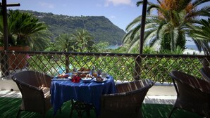 A table set with breakfast items, overlooking a mountainous landscape and a beach. - Semiramis Hotel De Charme (Forio)