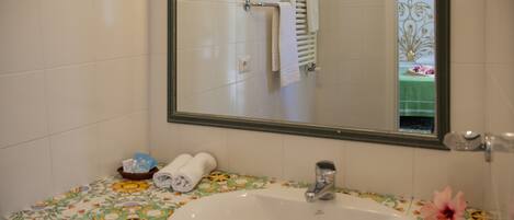 A bathroom with a white sink, a mirror, and a floral-patterned countertop.