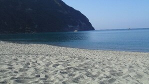 A beach with a sandy shore and a large cliff in the background. - Semiramis Hotel De Charme (Forio)