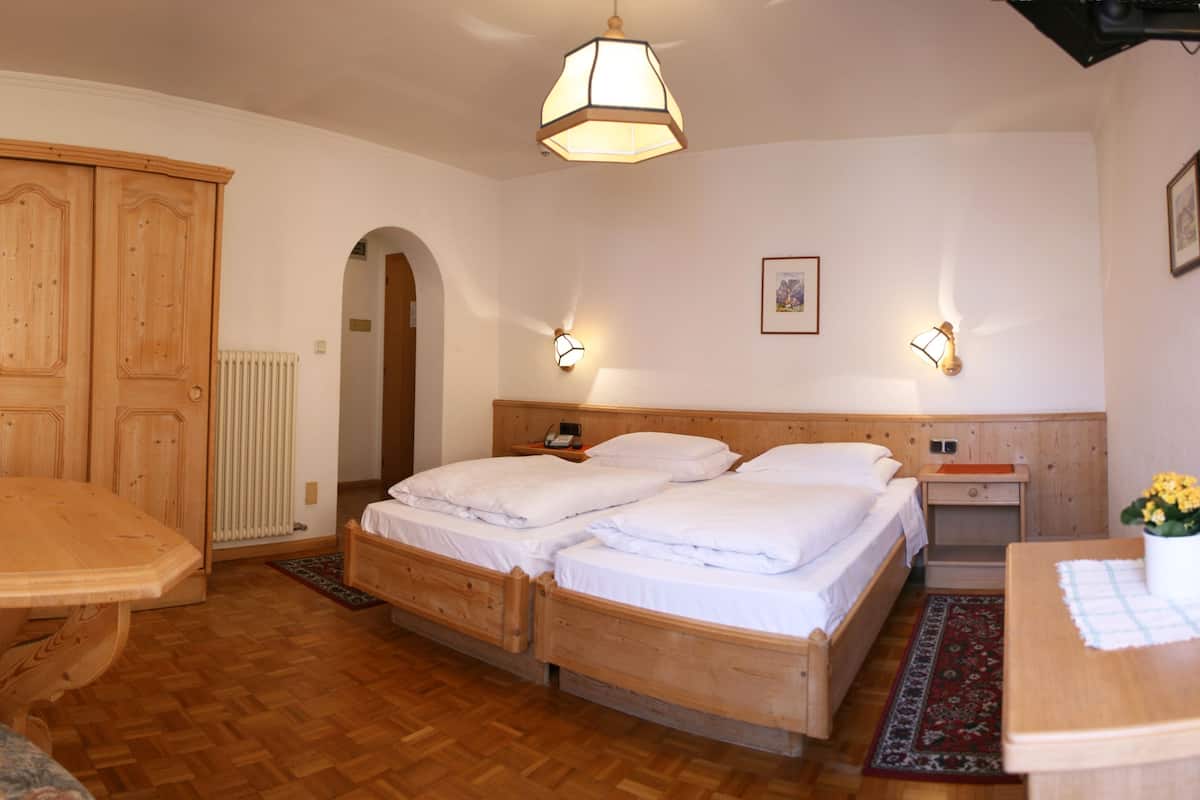 Una habitación con una cama de madera, una mesa de madera y un armario.