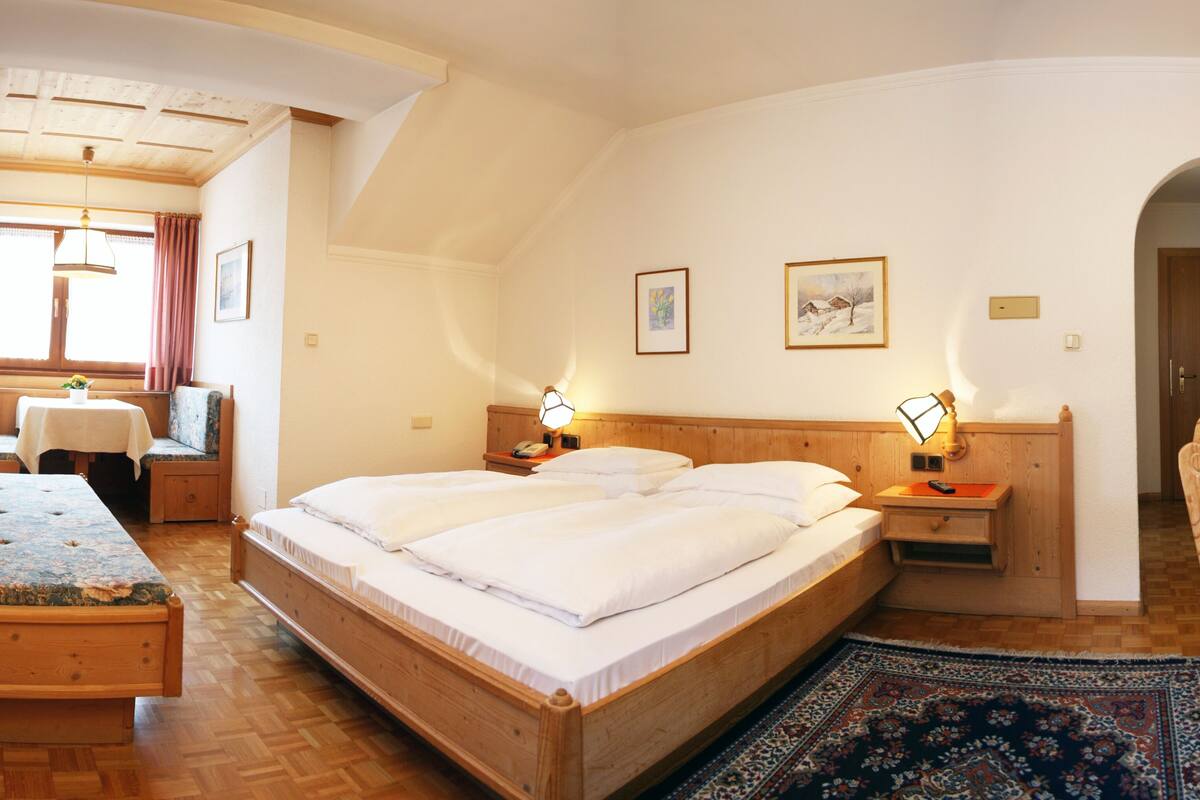 Un dormitorio acogedor con una cama grande, mesitas de noche, una mesilla auxiliar, un escritorio y una silla.