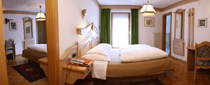 Une chambre d’hôtel avec un lit double, une table de chevet avec une lampe, une chaise, une fenêtre avec des rideaux et un miroir.
