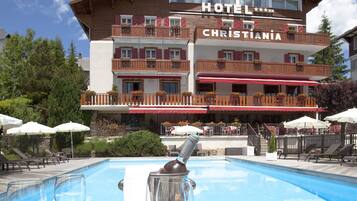 Een hotel met een zwembad, terras en een menukaart op de tafel.