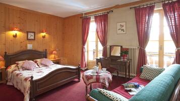 A cozy room with a wooden bed, a green sofa, a small table with a tea set, and a window with curtains.