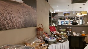 A breakfast buffet with various food items and beverages, a wine selection, and a decorative Buddha statue. - Hotel Castel (Ghent)