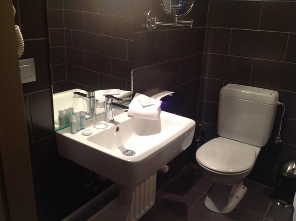 Un baño con lavamanos blanco, espejo e inodoro.