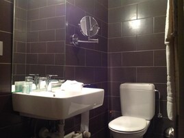Ein Badezimmer mit einem weißen Waschbecken, einem Spiegel und einer Toilette.