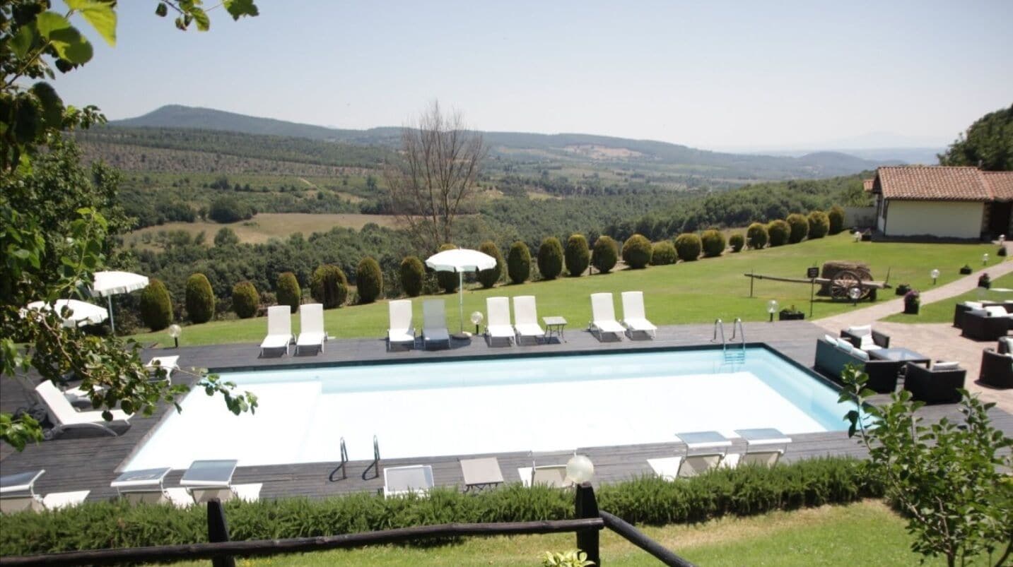 Una piscina con sillones de descanso y vistas al campo.