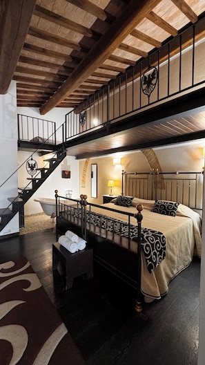 Une chambre avec un grand lit, un escalier en bois et une vue sur l’extérieur.
