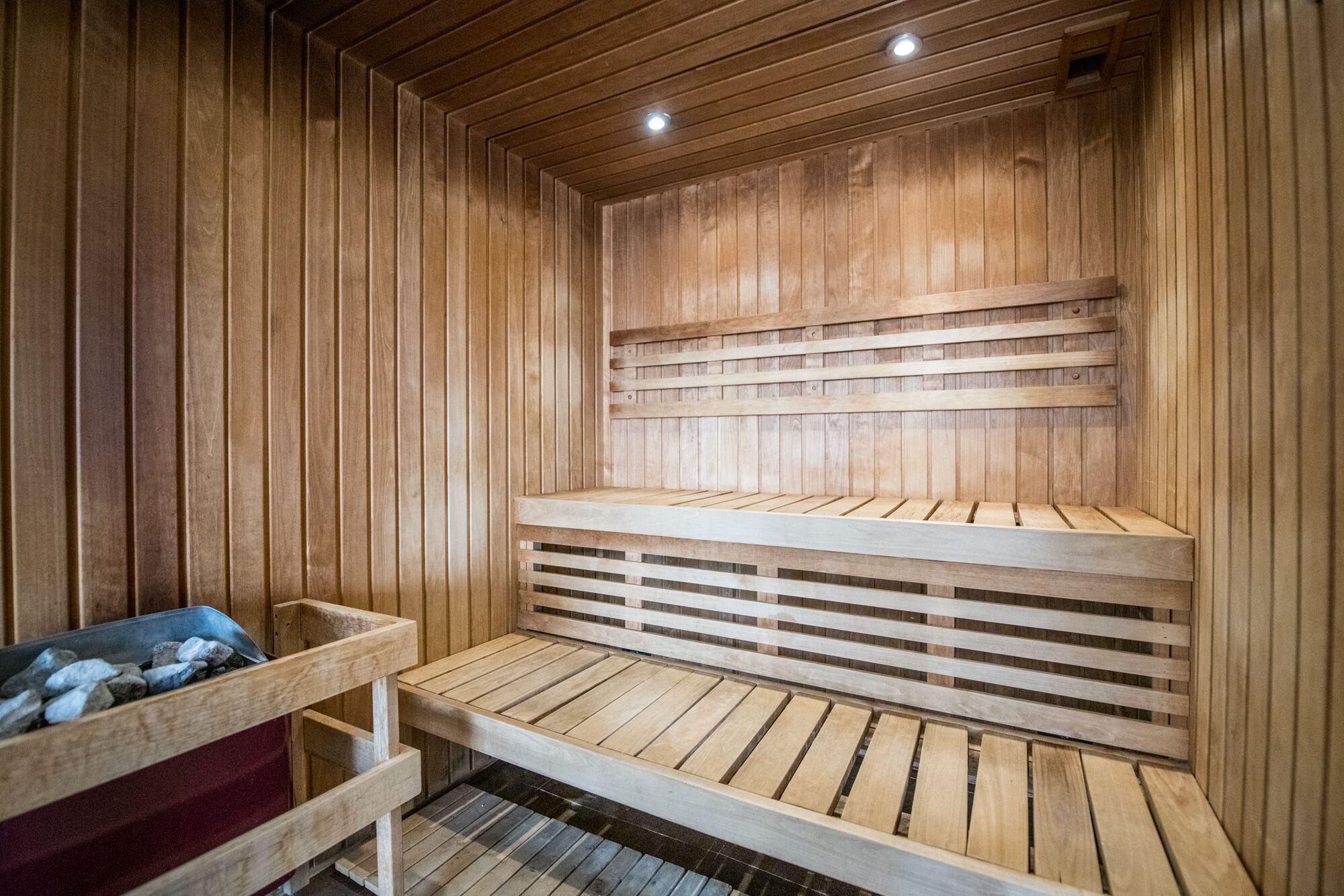 Un sauna en bois, doté de bancs et d’un récipient en métal servant de banc.
