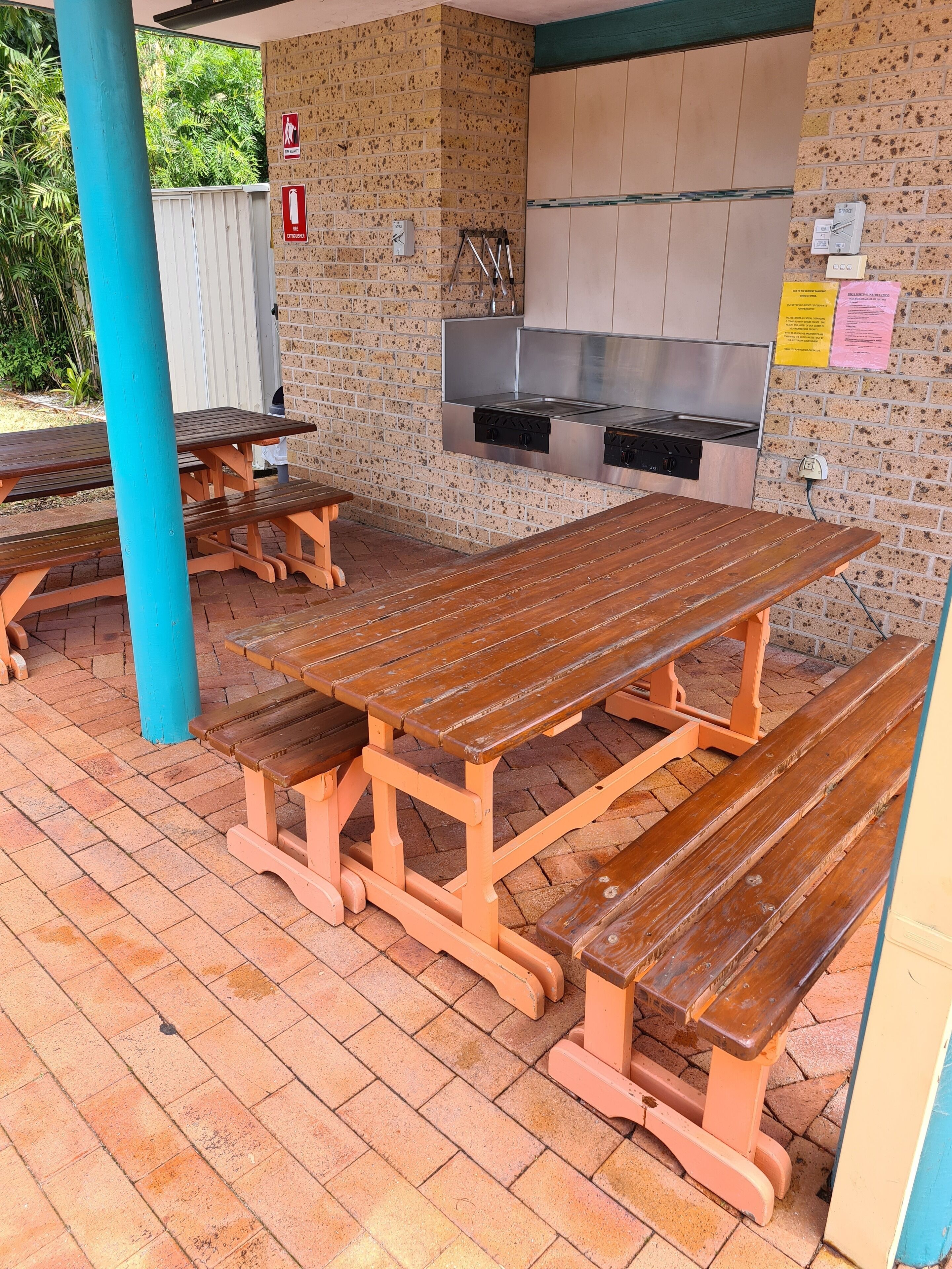 An outdoor patio with picnic tables and a built-in grill area.