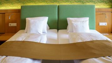 A double bed with a green headboard, white pillows, and a brown bedspread.