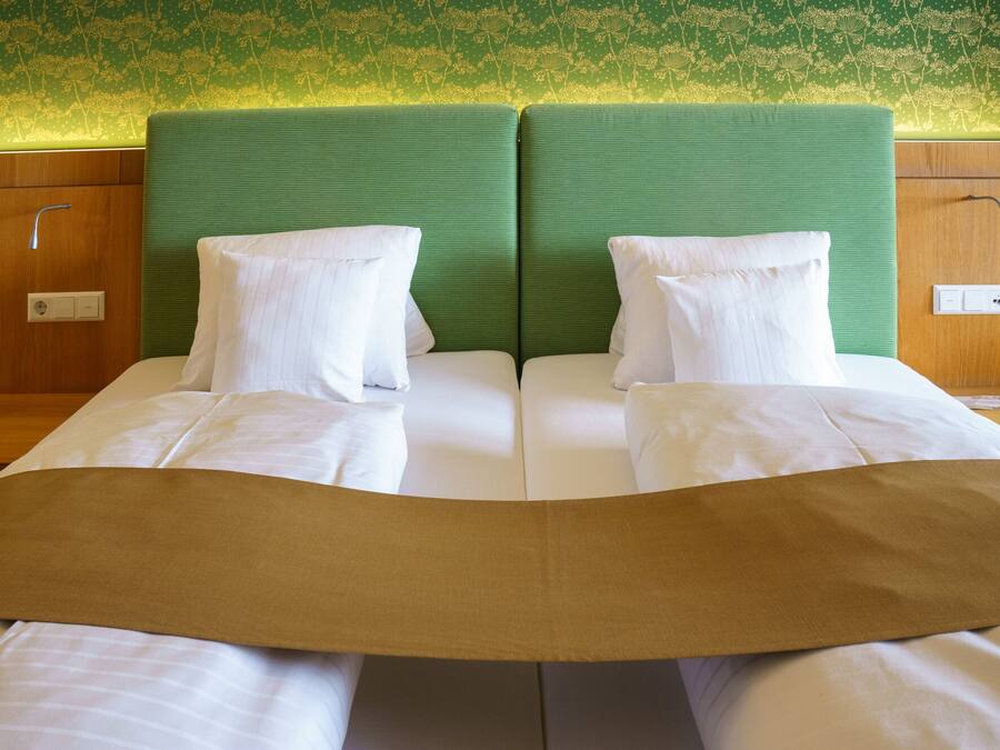 A double bed with a green headboard, white pillows, and a brown bedspread.