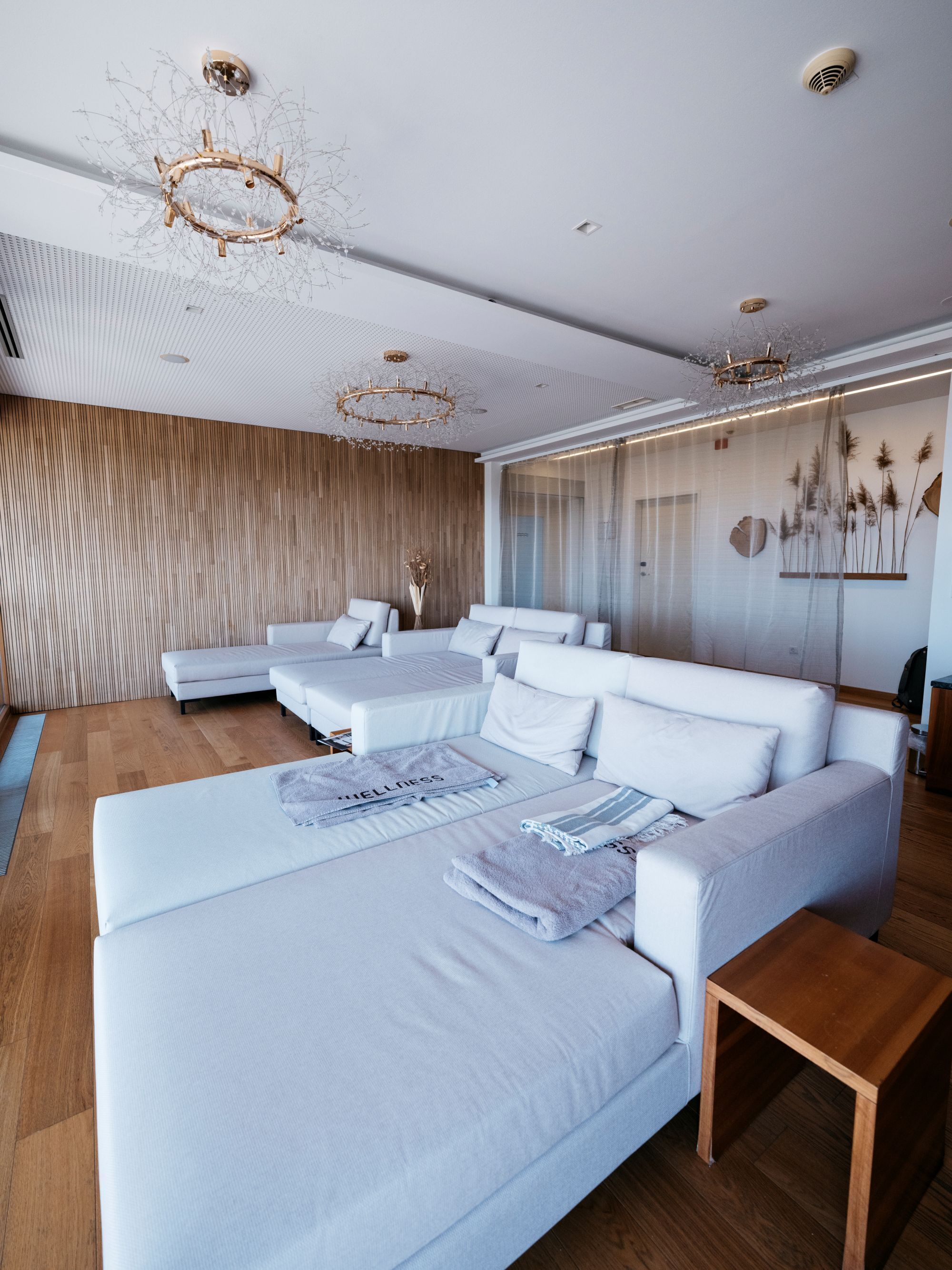Una habitación de hotel moderna con una cama grande, un sofá y suelo de madera.